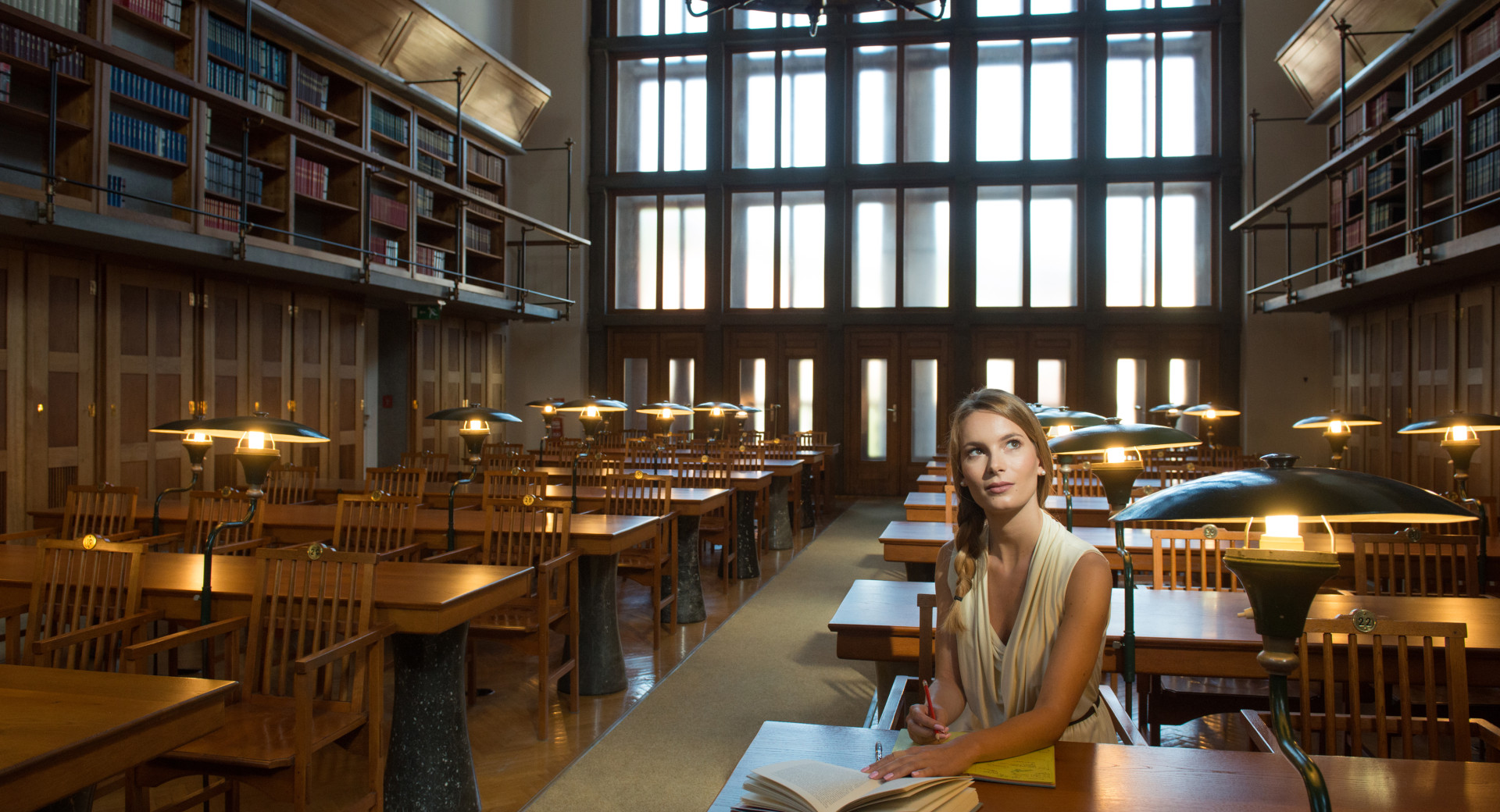 Notranjost narodne in univerzitetne knjižnice. V ospredju dekle s knjigo.