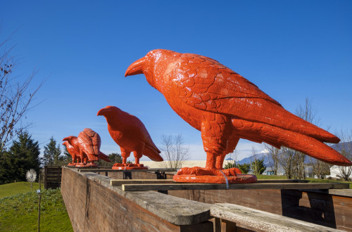 Velike skulpture ptic, pobarvane v rdečo barvo, na lesenih deskah med lesenima zidovoma – delo belgijskega umetnika Williama Sweetlovea, ki je na ogled v Arboretumu Volčji Potok (16. marec–22. september 2024)