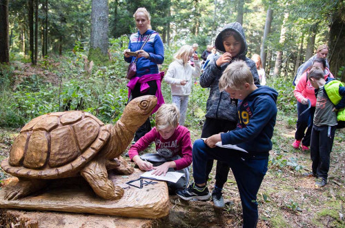 Otroci ob leseni želvi v gozdu.