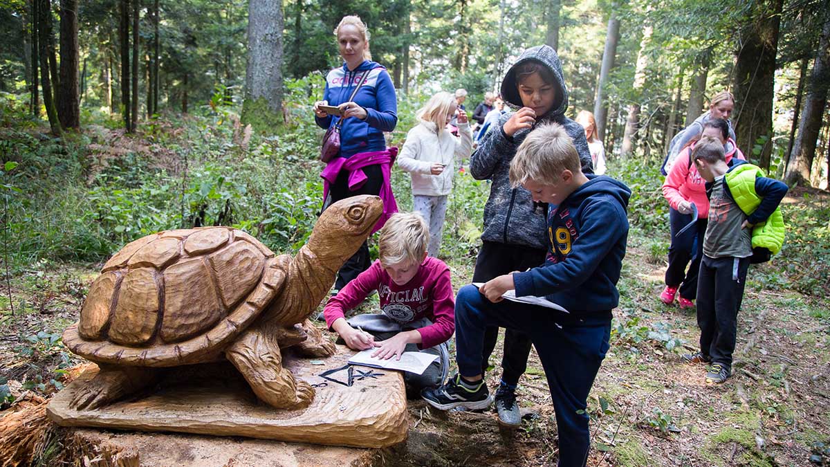 Otroci ob leseni želvi v gozdu.