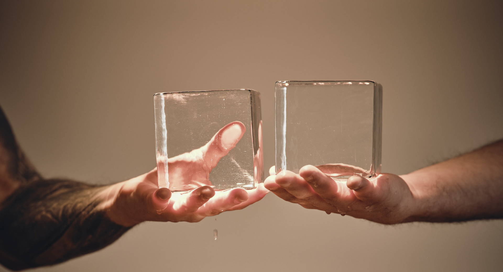 Dve roki, ki drzita dve veliki ledeni kocki nad veliko kocko ledu