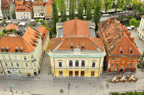 Panoramski pogled na filharmonijo z Ljubljanico v ozadju.