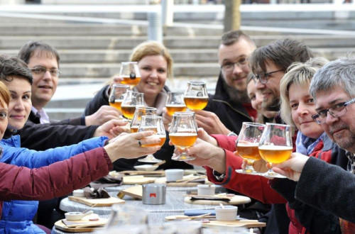 Skupina ljudi za mizo nazdravlja s pivom. 