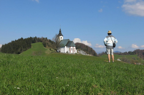 Pohodnik ogleduje cerkev in pokrajino.