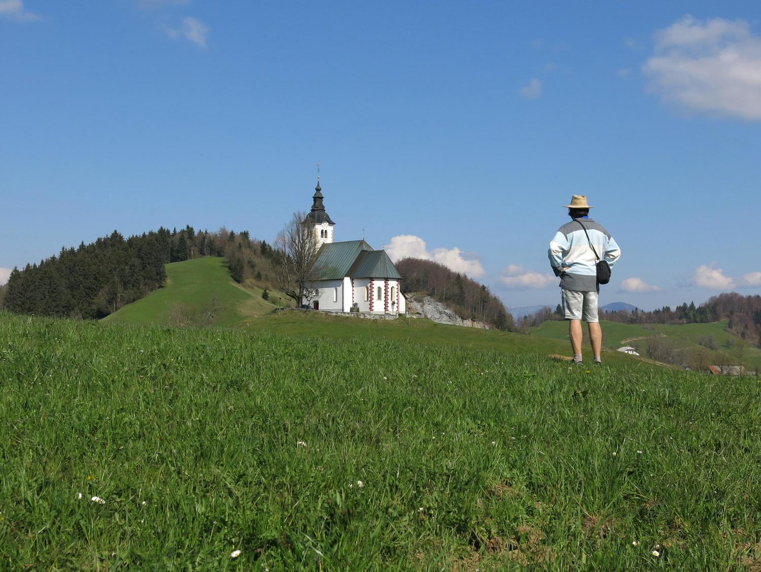 Pohodnik ogleduje cerkev in pokrajino.