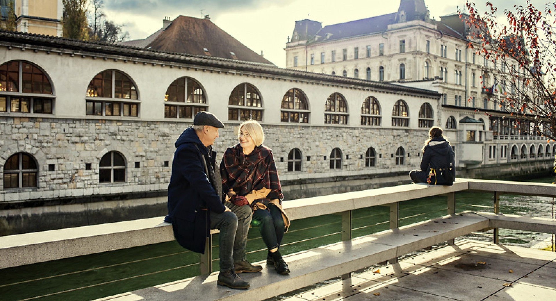 Par sedi ob Ljubljanici, v ozadju Plečnikove tržnice