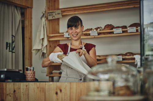 Rifuzl, trgovina brez plastične embalaže v Ljubljani – prodajalka daje kruh v papirnato vrečko