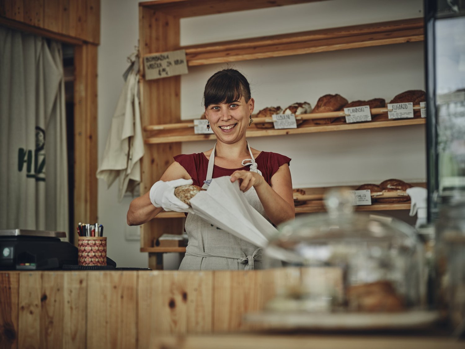 Rifuzl, trgovina brez plastične embalaže v Ljubljani – prodajalka daje kruh v papirnato vrečko