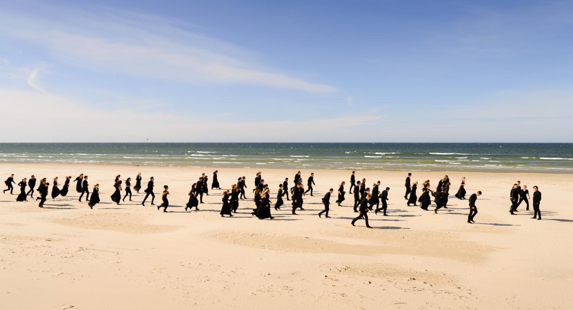 Skupina ljudi teče po plaži