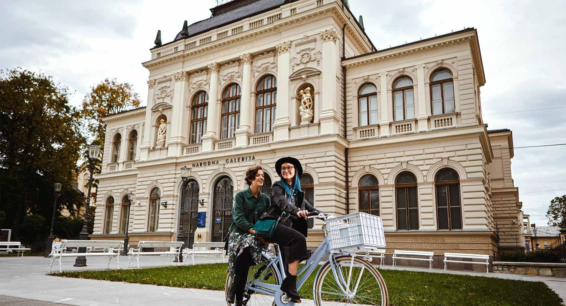 Ženski na kolesu pred veliko belo stavbo