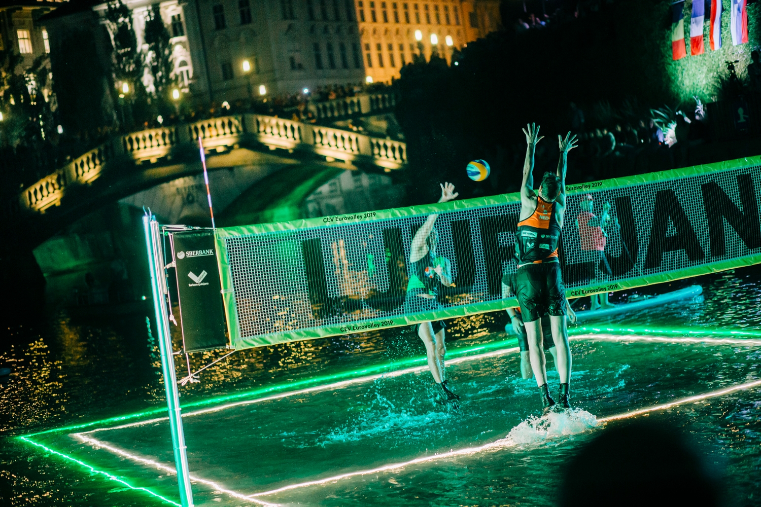 Igranje odbojke na osvetljenem igrišču na Ljubljanici v središču Ljubljane