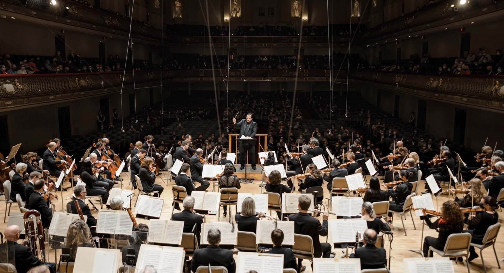 Simfonicni orkester z dirigentom med nastopom.