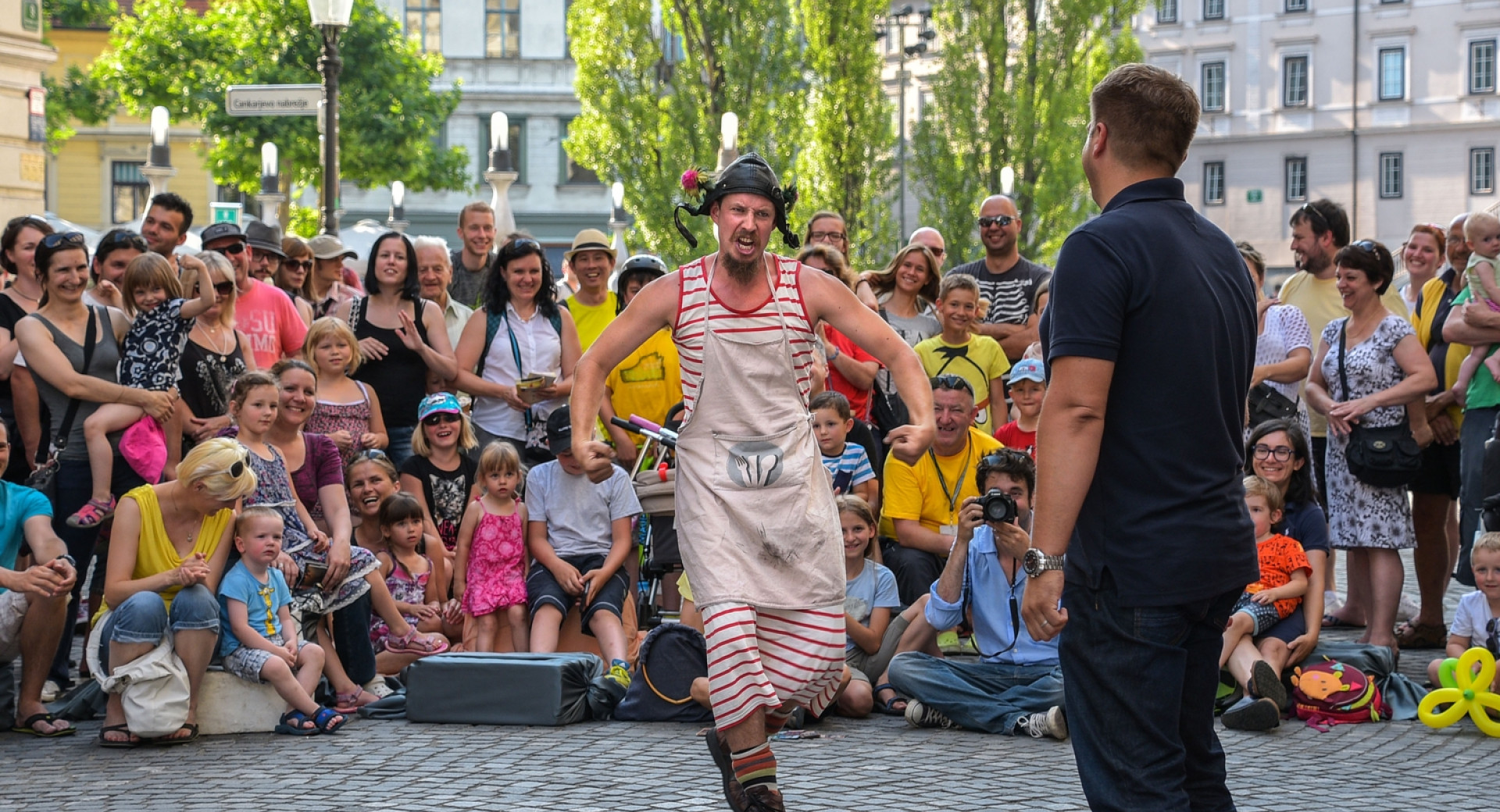 Nastopajoča na Ani Desetnici, festivalu uličnega gledališča v Ljubljani, okoli njiju občinstvo