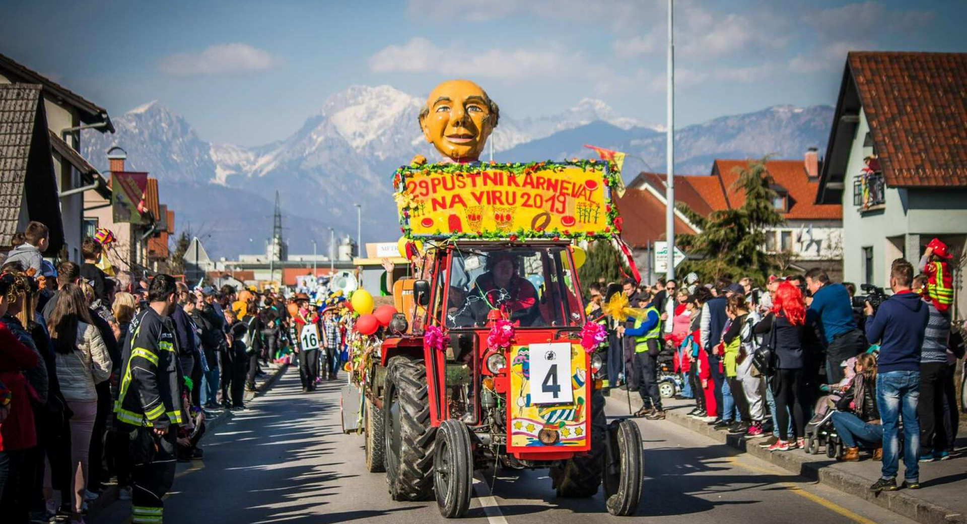 Pustni karneval na Viru; na fotografiji maske na traktorju, za njimi sprevod, ob strani občinstvo