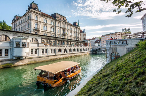 Turistična ladjica na Ljubljanici; v ozadju Plečnikove tržnice.