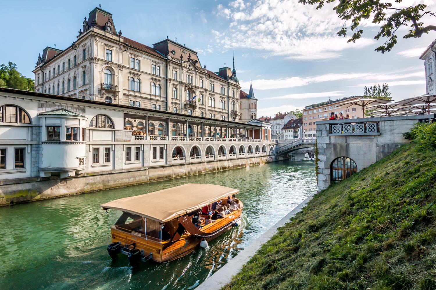 Turistična ladjica na Ljubljanici; v ozadju Plečnikove tržnice.