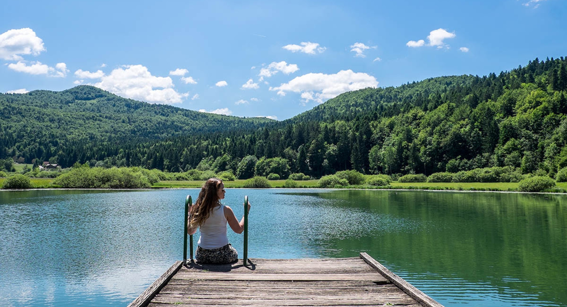 Ženska sedi ob Podpeškem jezeru