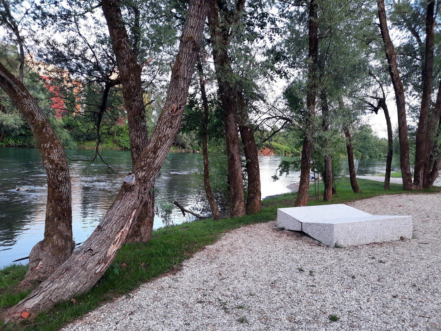 Nova plaža ob Savi, v bližini kopališča Laguna, v Ljubljani; na fotografiji betonski ležalnik na prodnati plaži in v zavetju dreves ob reki