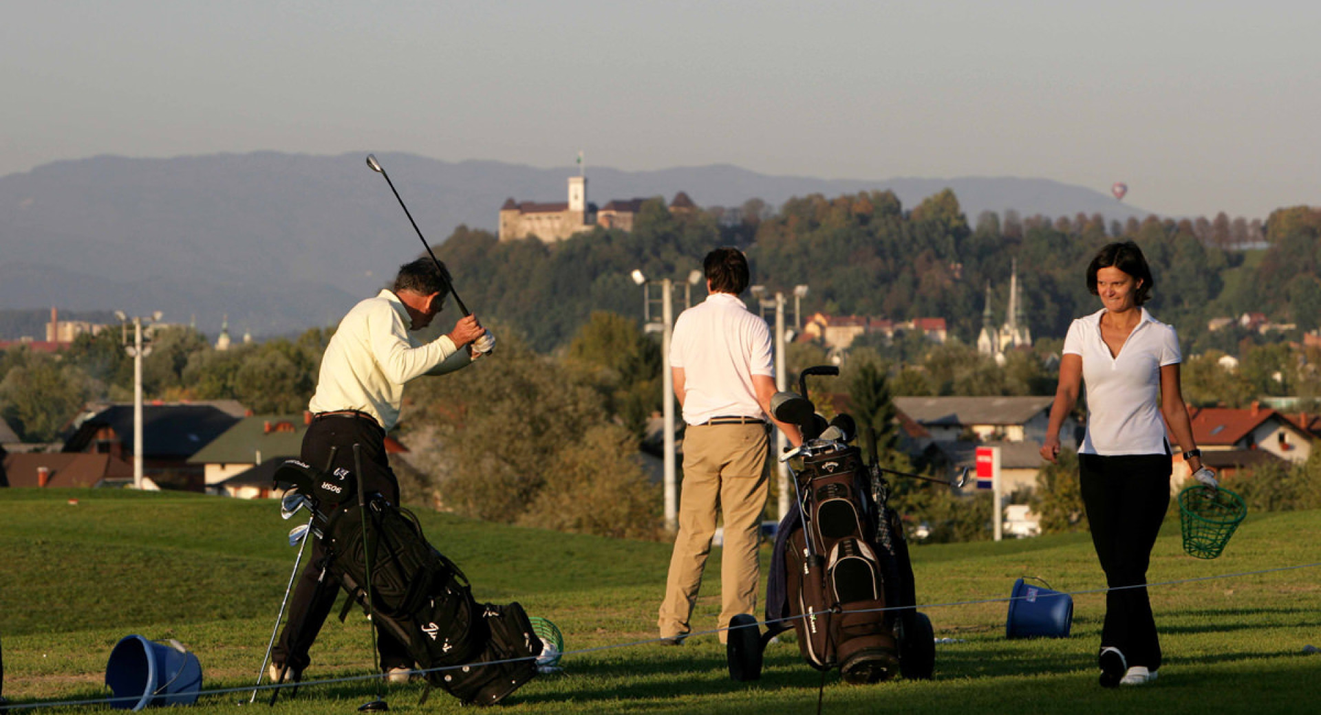 Trije golfisti. V ozadju Ljubljanski grad.