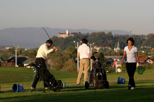 Trije golfisti. V ozadju Ljubljanski grad.