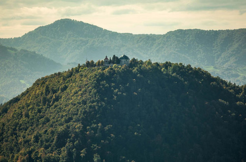 Panoramska slika gore s cerkvico na vrhu.