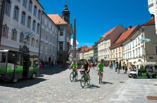 Trije kolesarji na mestnem trgu v Ljubljani.