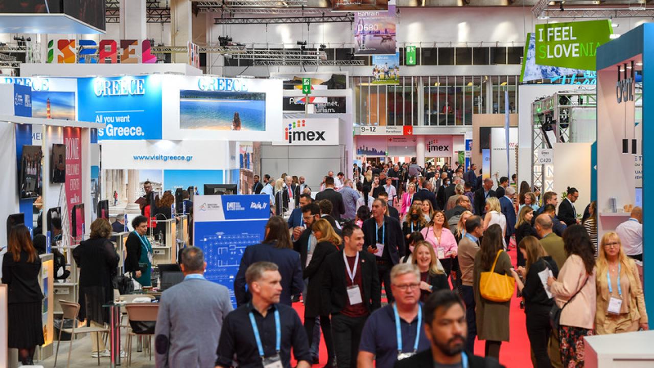 Obiskovalci hodijo med predstavitvami na mednarodni borzi industrije srečanj IMEX v Frankfurtu, maj 2023
