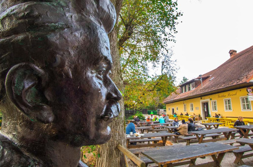 Cankarjev vrh na Rožniku v Ljubljani; v ospredju kip Ivana Cankarja, v ozadju gostje Gostilne Rožnik, ki sedijo ob mizah
