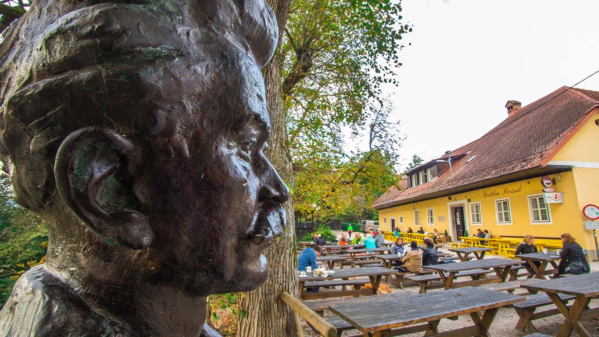 Cankarjev vrh na Rožniku v Ljubljani; v ospredju kip Ivana Cankarja, v ozadju gostje Gostilne Rožnik, ki sedijo ob mizah