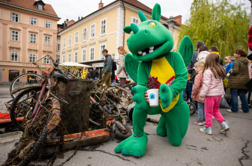 Ljubljanska maskota, Zmajček, na Čevljarskem mostu, pred odpadki, ki so jih izvlekli iz Ljubljanice v okviru akcije Za lepšo Ljubljano, april 2022