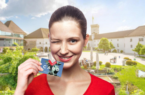 Ženska drži v rokah Turistično kartico Ljubljane, v ozadju notranjos dvorišče Ljubljanskega gradu