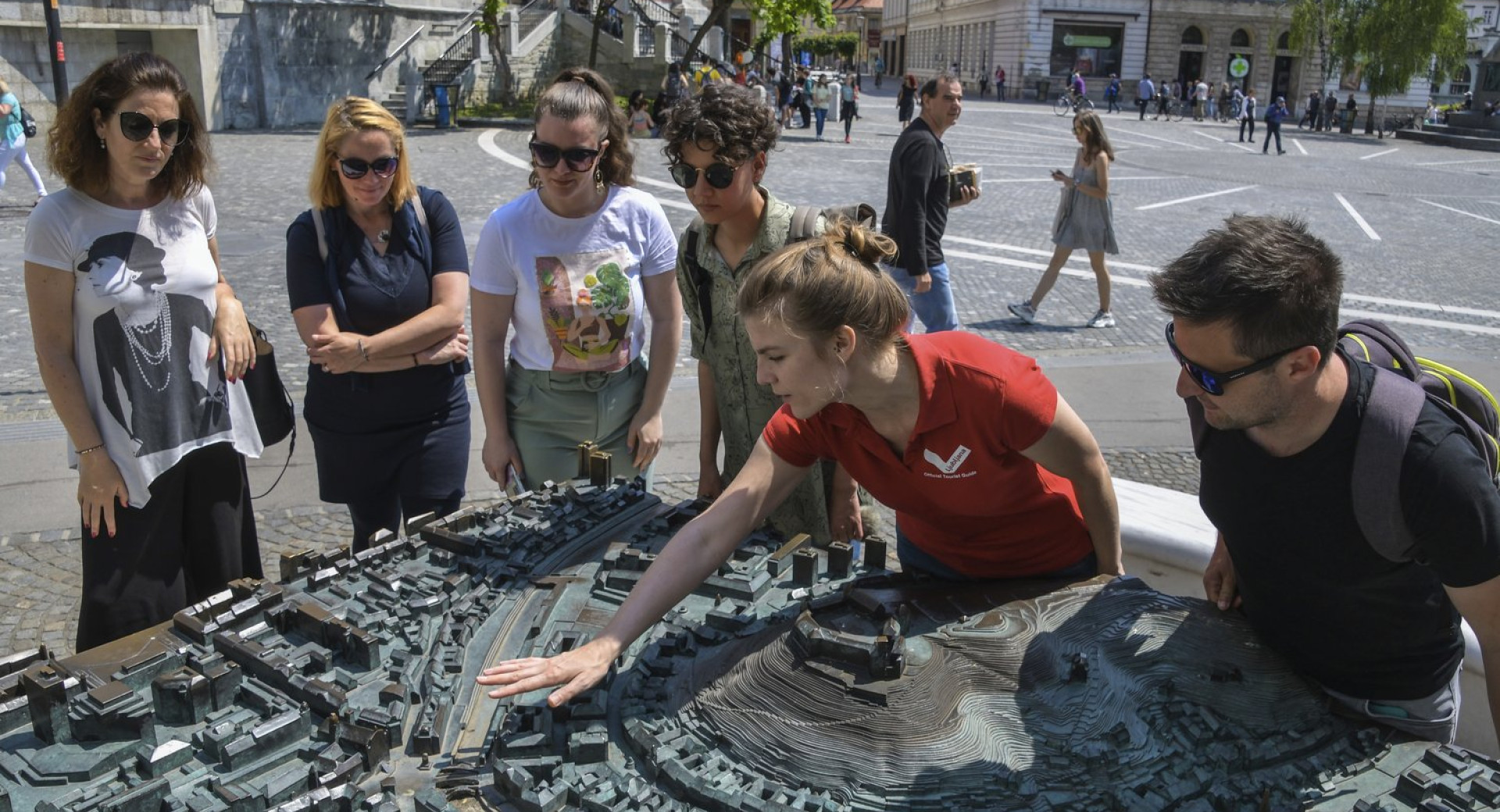 Turistična vodnica s skupino obiskovalcev pred maketo Ljubljane na Prešernovem trgu