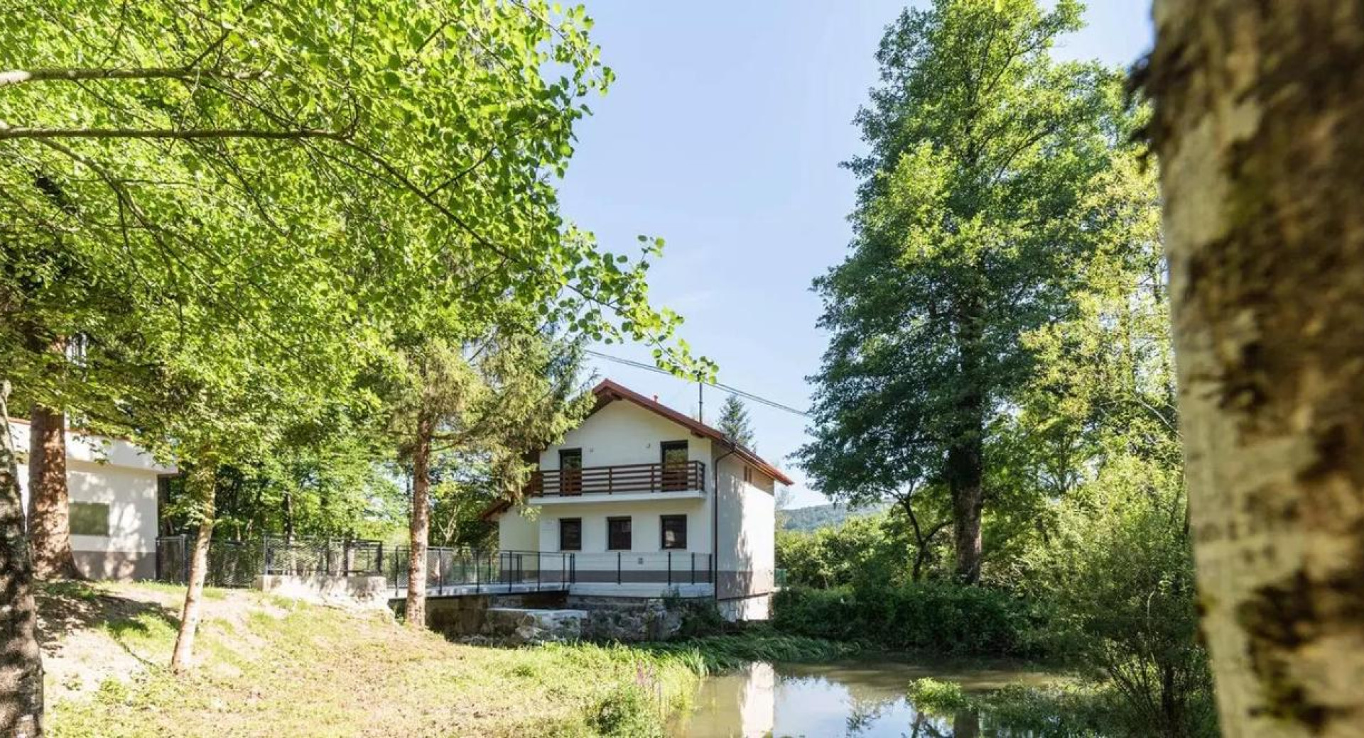 Žabja hiša na Radenskem polju pri Grosupljem, prvo naravovarstveno središče v Sloveniji, ob njej rečica in drevesa