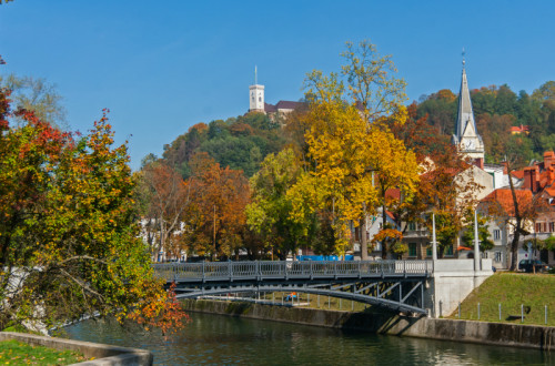 Ljubljanica jeseni. V ozadju most, cerkev in Ljubljanski grad.