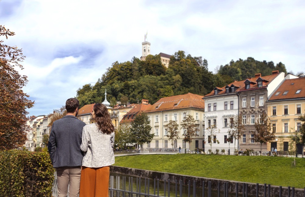 Zaljubljen par ob Ljubljanici. V ozadju ljubljanski grad.
