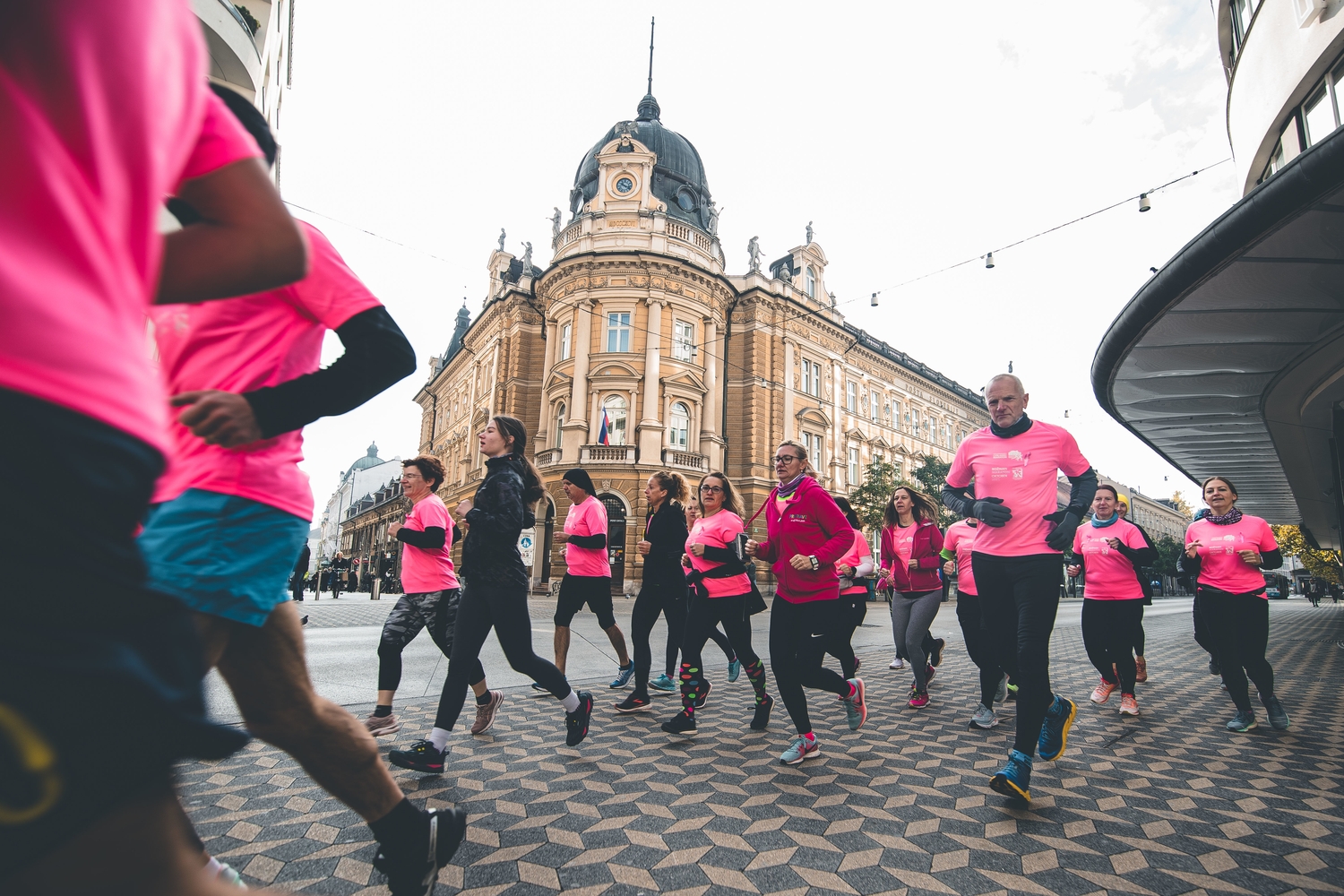Tekači v Ljubljani v rožnatih majicah tečejo na Rožnatem maratonu, 2021