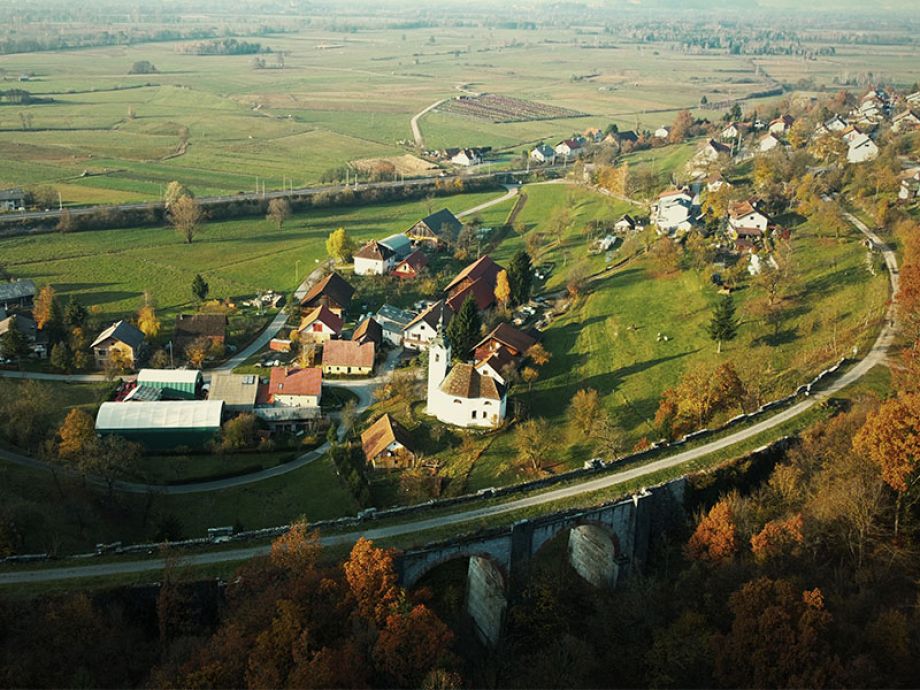 Pogled na borovniški Paški most z naseljem hiš in cerkvijo iz zraka