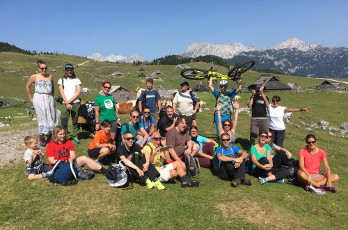 Skupina pohodnikov na Veliki planini. V ozadju planinske koče in gore.