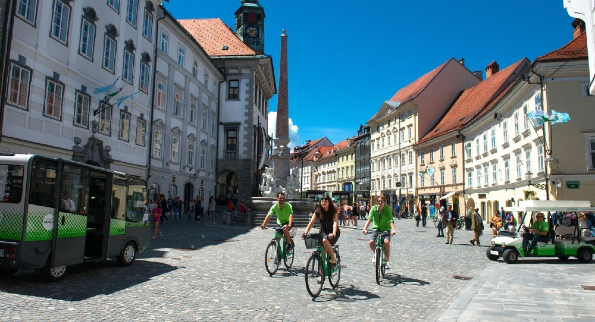 Trije kolesarji na mestnem trgu v Ljubljani.