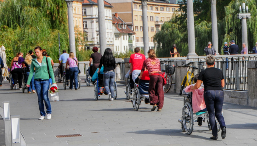 Mestni utrip - sprehajalci na invalidskih vozičkih s spremljevalci.