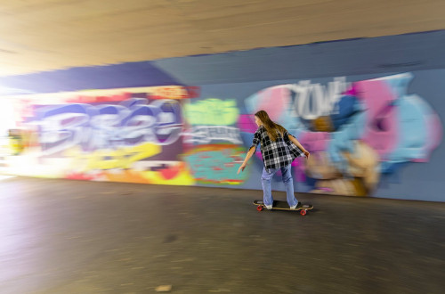 Mlado dekle rolka pred barvnimi grafiti. Mlado dekle rolka v podhodu.
