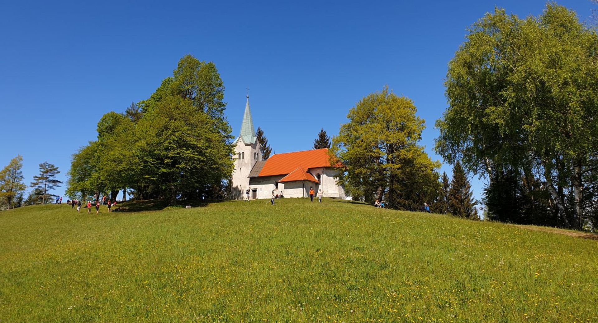 A white church on top of a green hill.