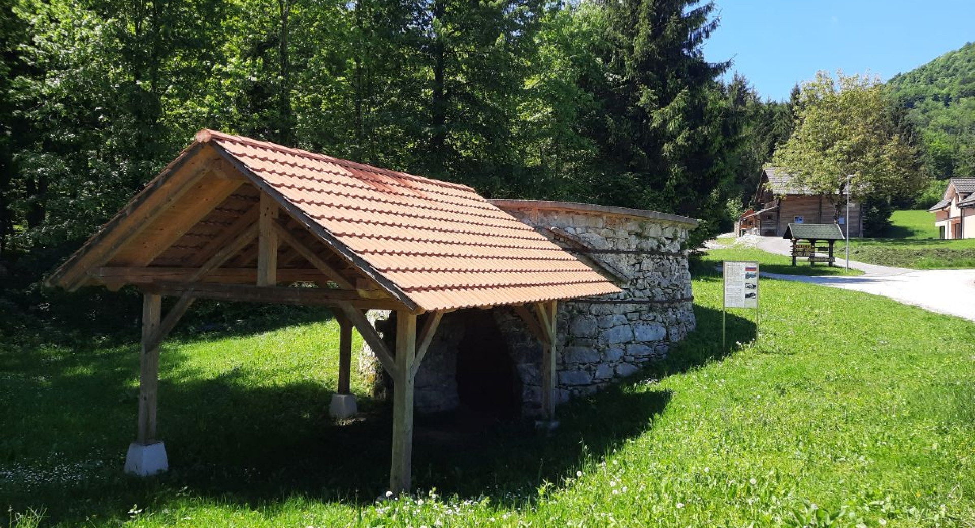 Ob poti stoji majhna tenda s streho, ob njej pa izpostavljeno izhodisce iz apnenca. V daljavi ob cesti stojijo lesene hise.