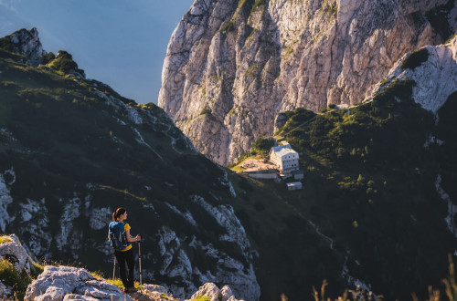 Pohodnica, v ozadju planinska koča na Kamniškem sedlu.