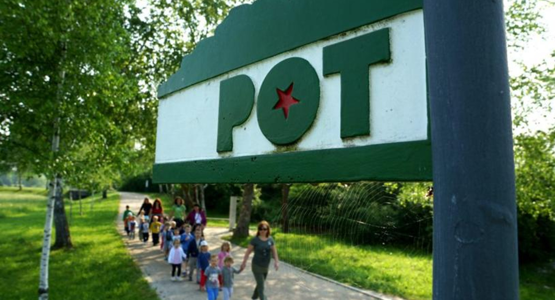 Velik napis Pot, v ozadnju pohodniki.