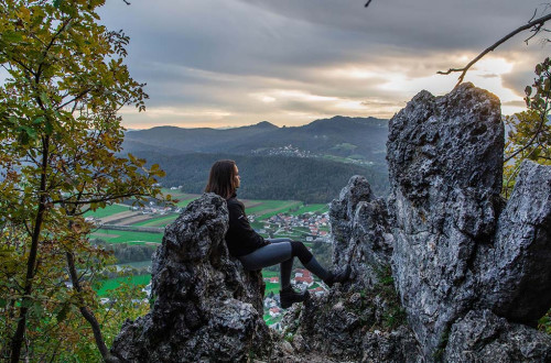 Dekle naslonjeno na skalo, v ozadju pogled na dolino.