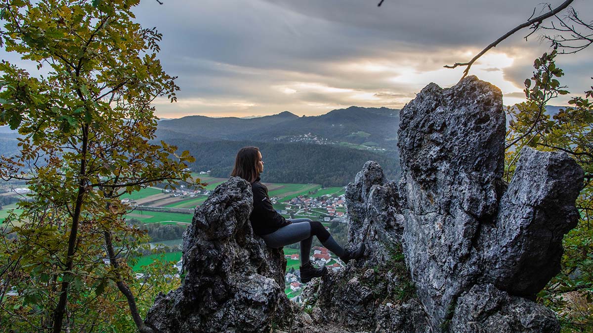 Dekle naslonjeno na skalo, v ozadju pogled na dolino.