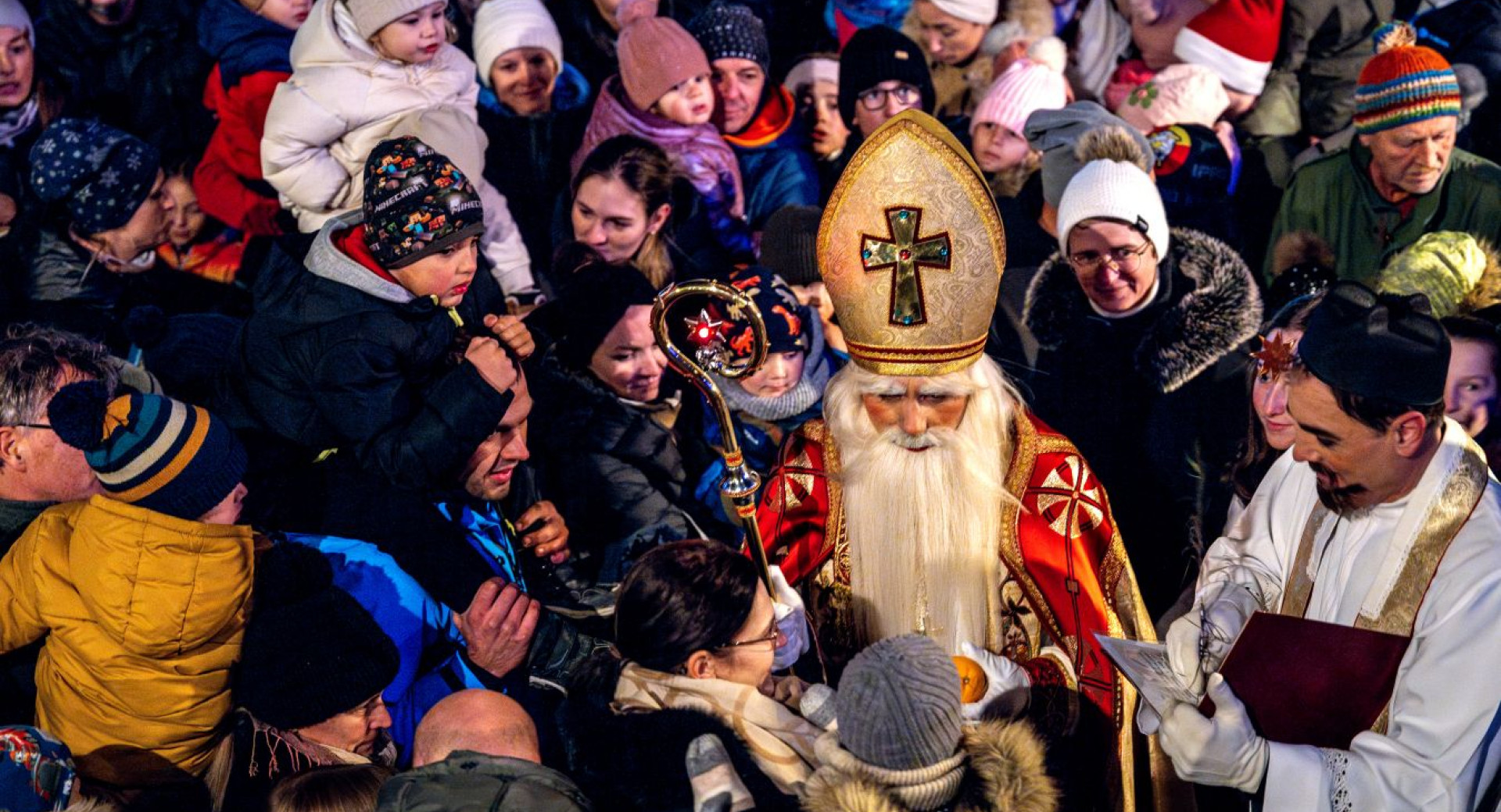 Saint Nicholas is surrounded by children and greets them.