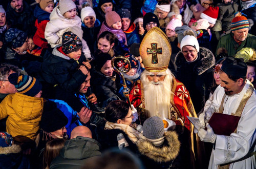 Saint Nicholas is surrounded by children and greets them.
