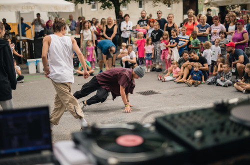 Ulicna breakdance predstava pred obcinstvom vseh generacij z DJ-jem in gramofonom na odprtem dogodku v mestnem okolju.